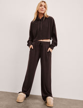 model wearing brown ribbed wide leg pants with a drawcord at waistband against a plain background.
